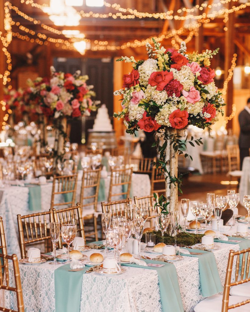 Yellow light garlands hang over the dinner tables decorated with pink bouquets